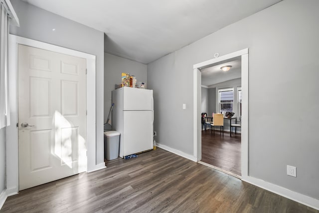 interior space with freestanding refrigerator, baseboards, and dark wood-style flooring