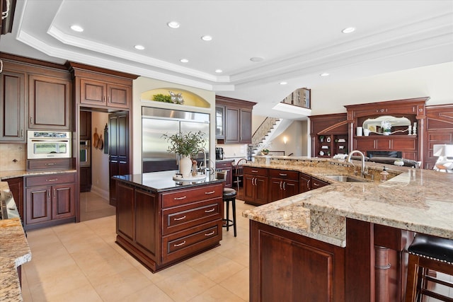 2122 Grange Rd, Buchanan, MI 49107 - kitchen featuring a sink, appliances with stainless steel finishes, a tray ceiling, a breakfast bar, and backsplash