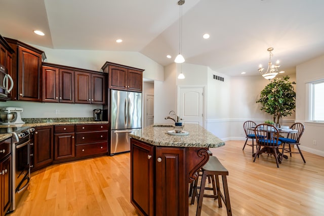 2122 Grange Rd, Buchanan, MI 49107 - kitchen with stainless steel appliances, light wood finished floors, a kitchen breakfast bar, a sink, and decorative light fixtures