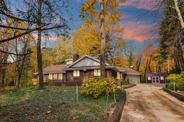 view of front of house with brick siding, a chimney, a garage, an outbuilding, and driveway