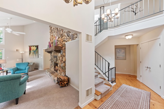 interior space featuring stairway, ceiling fan with notable chandelier, visible vents, and a towering ceiling