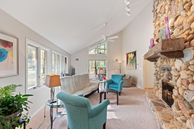 carpeted living area with a stone fireplace, a healthy amount of sunlight, rail lighting, and a ceiling fan