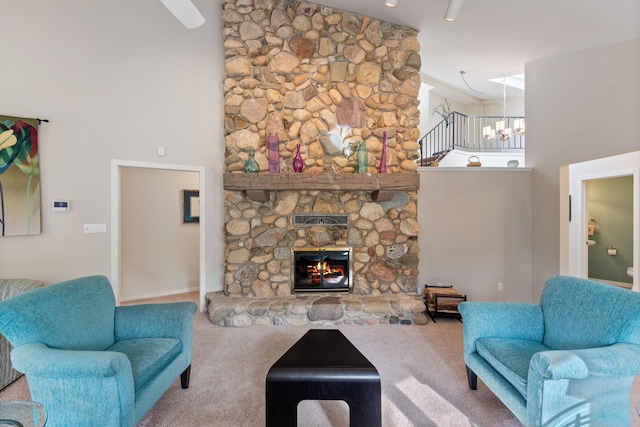 living area with a stone fireplace, carpet, an inviting chandelier, and a towering ceiling