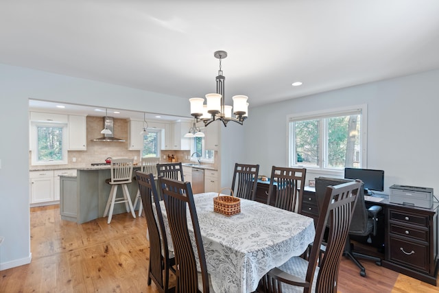 dining area with light wood-type flooring, plenty of natural light, and a chandelier