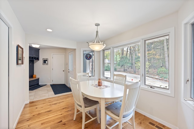 dining space with light wood-style flooring, baseboards, and visible vents