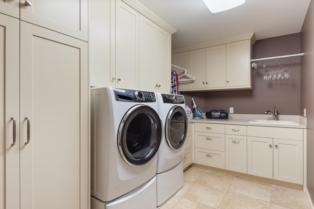 laundry room with a sink, cabinet space, light tile patterned floors, and washer and clothes dryer