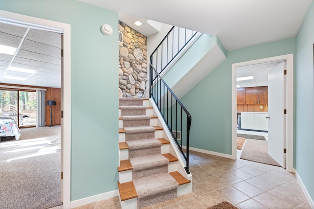 stairs with a drop ceiling, baseboards, carpet flooring, and tile patterned flooring