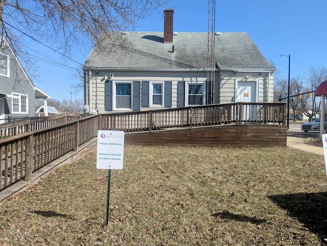 back of house with a lawn, roof with shingles, and a chimney