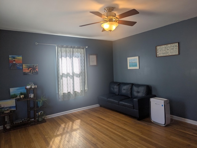 living area featuring baseboards, wood-type flooring, and ceiling fan