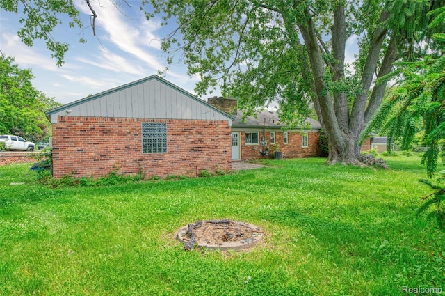 2810 Otsego Rd, Waterford, MI 48328 - view of property exterior featuring a yard, an outdoor fire pit, brick siding, and a chimney