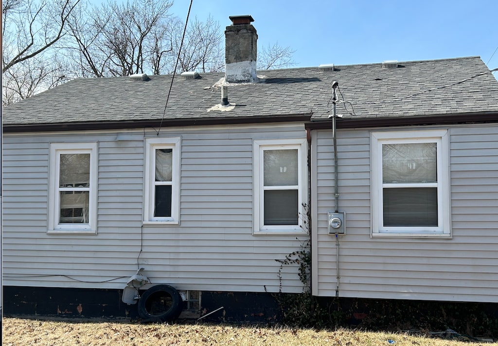 rear view of property with roof with shingles and a chimney