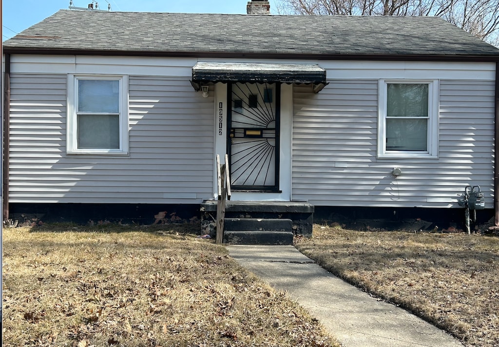 property entrance featuring a shingled roof and a chimney