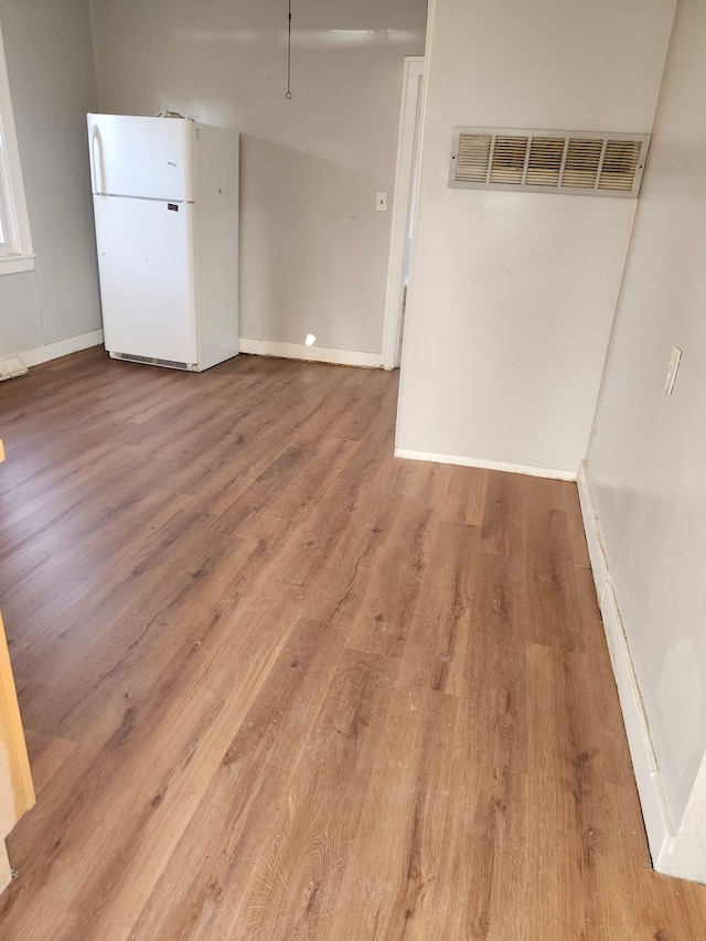 spare room featuring visible vents, baseboards, and wood finished floors