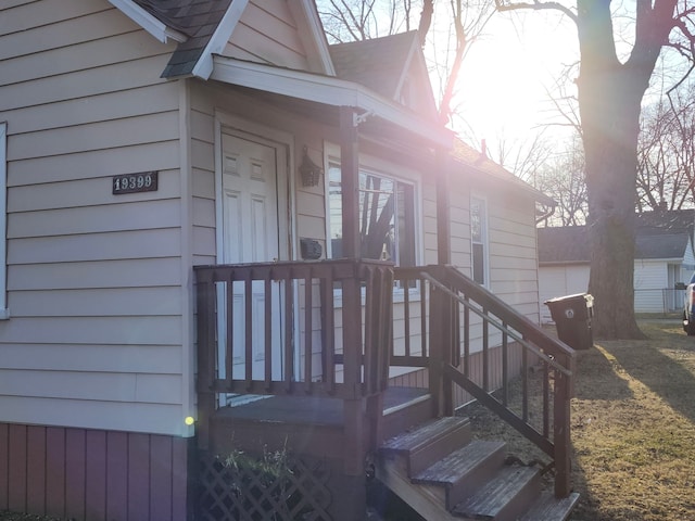 view of exterior entry featuring roof with shingles