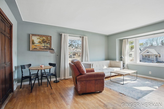 living area with light wood-type flooring, plenty of natural light, and baseboards