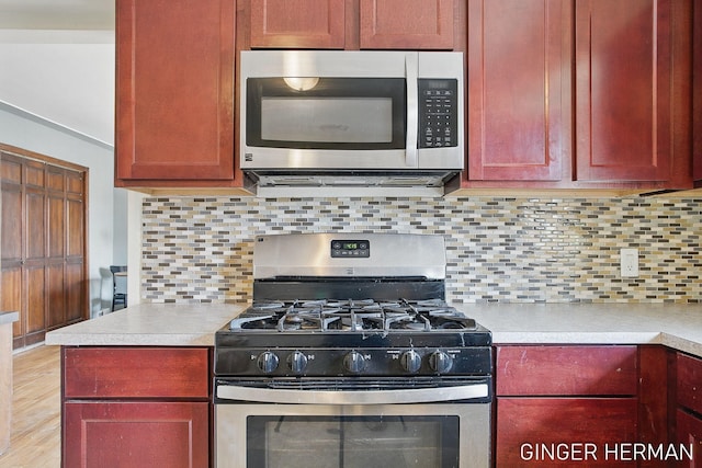 kitchen featuring light wood-style flooring, stainless steel appliances, decorative backsplash, light countertops, and dark brown cabinets