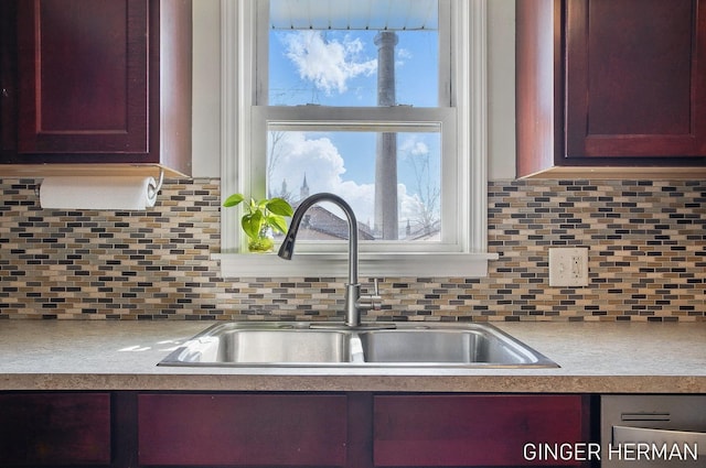 kitchen featuring backsplash, light countertops, and a sink