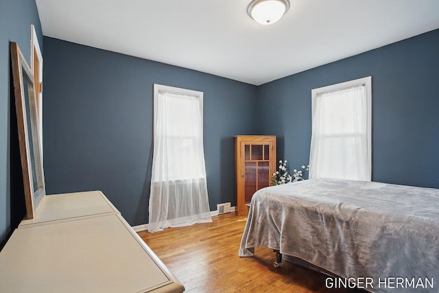 bedroom featuring visible vents, baseboards, and wood finished floors