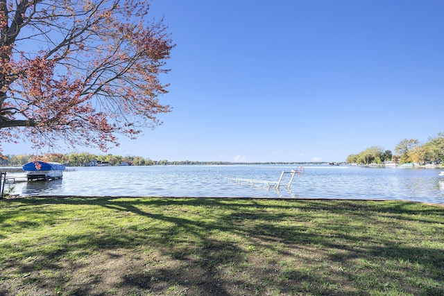 view of dock with a lawn and a water view