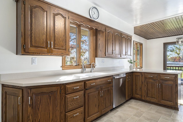 kitchen with stainless steel dishwasher, a peninsula, light countertops, and a sink