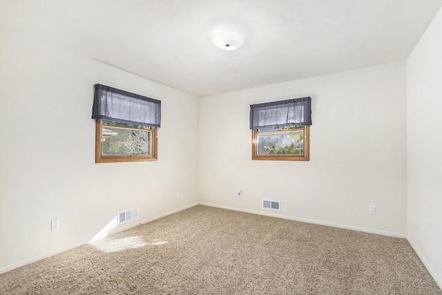 carpeted empty room featuring visible vents and baseboards