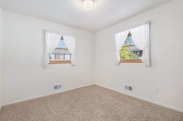 empty room featuring visible vents, carpet flooring, and baseboards