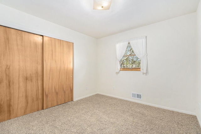 unfurnished bedroom with carpet flooring, baseboards, visible vents, and a closet