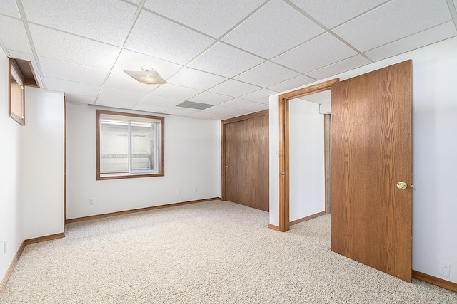 unfurnished bedroom with a closet, baseboards, a paneled ceiling, and carpet