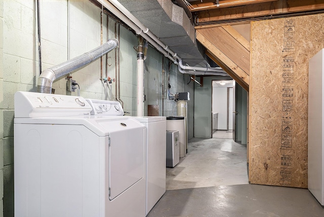 clothes washing area featuring washer and dryer, concrete block wall, and laundry area