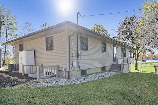 view of side of home with a yard, central AC, and fence