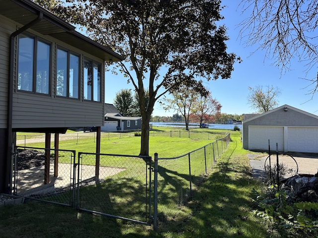 view of yard with a gate, fence, an outdoor structure, a garage, and a water view