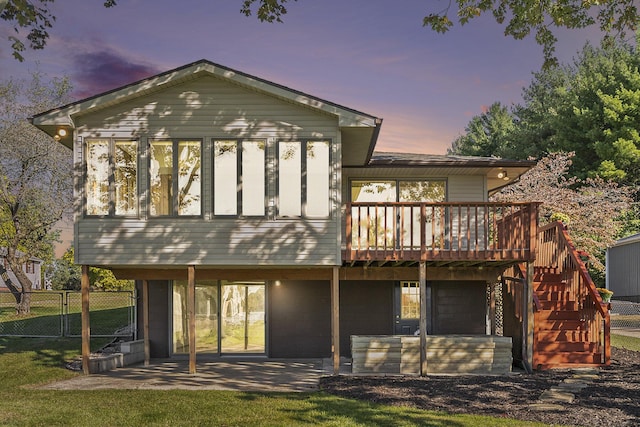 back of house at dusk with stairway, a patio area, fence, and a wooden deck