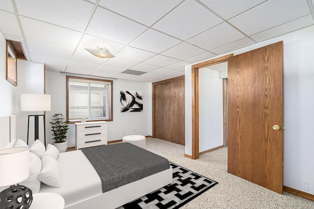 carpeted bedroom featuring a closet, a drop ceiling, and baseboards