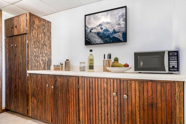 bar with tile patterned floors, a drop ceiling, and white microwave