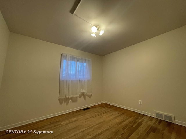 spare room featuring visible vents, dark wood-type flooring, and baseboards