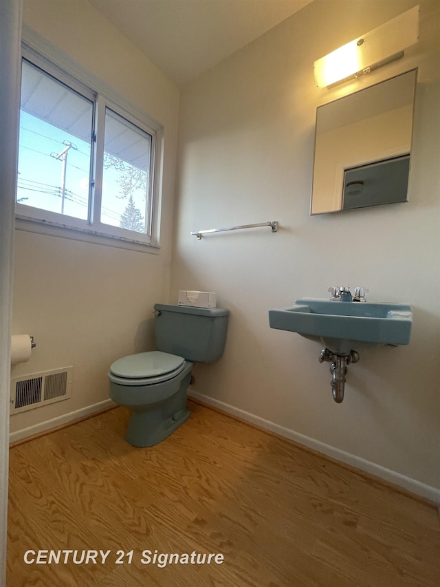 bathroom with visible vents, toilet, baseboards, and a sink