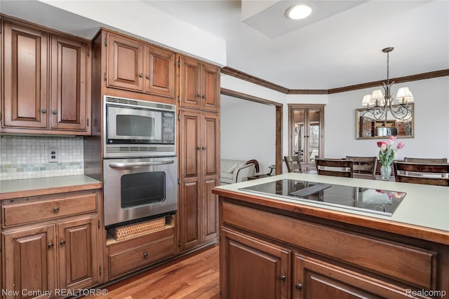 6750 Limerick Ln, Troy, MI 48098 - kitchen with appliances with stainless steel finishes, a chandelier, tasteful backsplash, light countertops, and decorative light fixtures