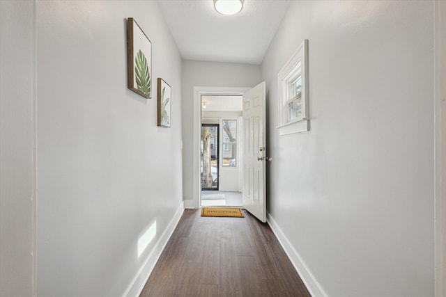 hallway featuring baseboards and dark wood-style floors