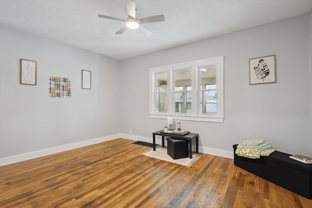 interior space featuring hardwood / wood-style floors, visible vents, baseboards, and ceiling fan