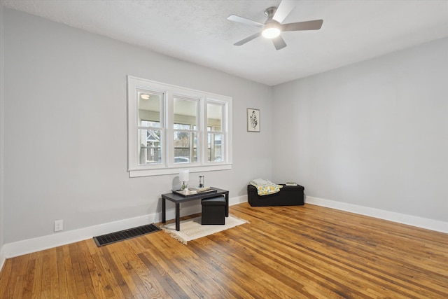 spare room with visible vents, ceiling fan, baseboards, and hardwood / wood-style flooring