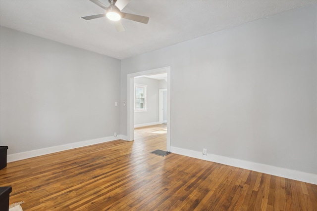 empty room featuring ceiling fan, visible vents, baseboards, and hardwood / wood-style floors