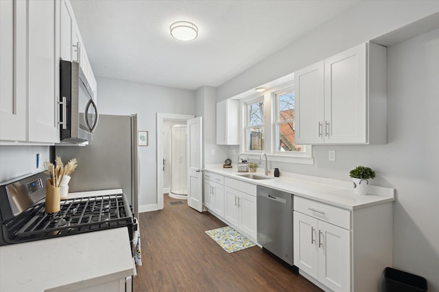 kitchen featuring a sink, appliances with stainless steel finishes, dark wood-style floors, and white cabinetry