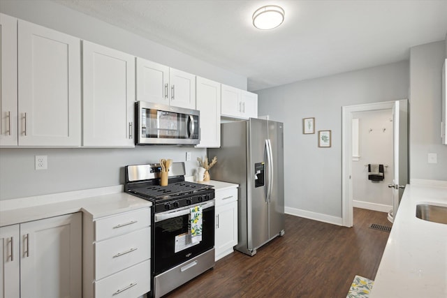 kitchen featuring dark wood-style floors, white cabinets, stainless steel appliances, and light countertops