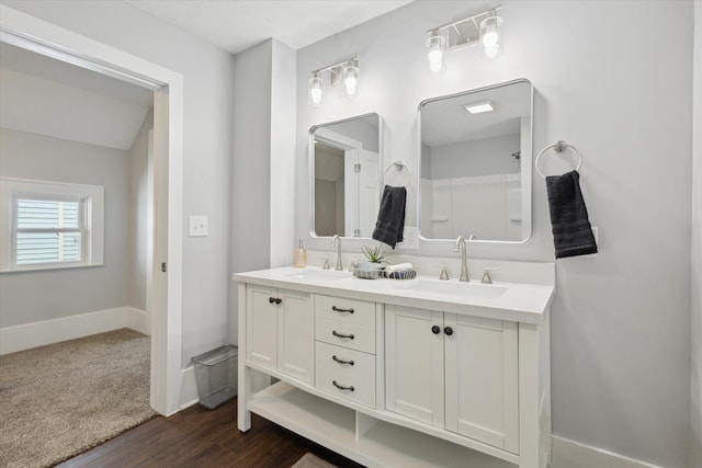 full bathroom with double vanity, wood finished floors, baseboards, and a sink