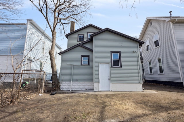 back of property with fence and a chimney