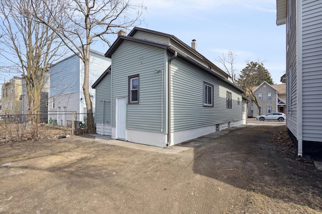 view of side of property with a chimney and fence