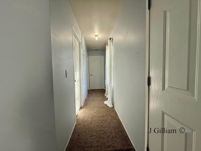 hallway with visible vents, baseboards, and carpet flooring