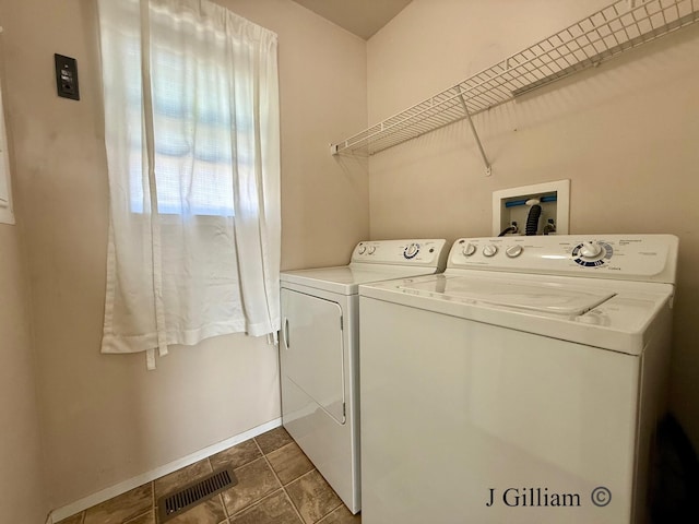 washroom featuring laundry area, dark tile patterned floors, visible vents, and washing machine and clothes dryer