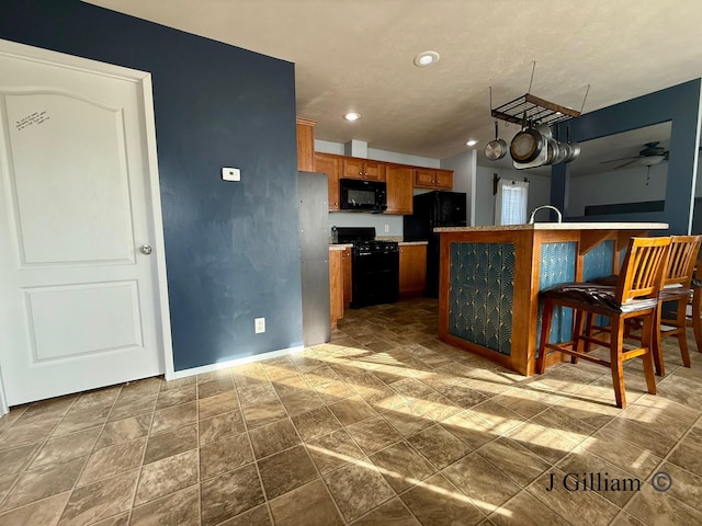 kitchen featuring baseboards, recessed lighting, brown cabinets, black appliances, and a ceiling fan