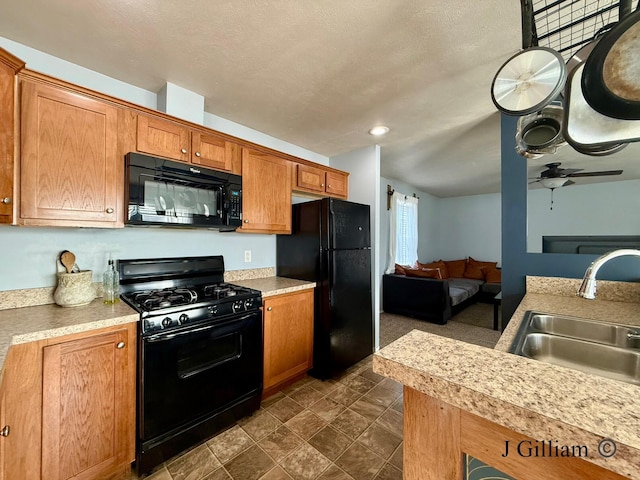 kitchen featuring a ceiling fan, brown cabinets, a sink, black appliances, and open floor plan